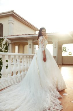 Beyaz bir gelinlikle çok güzel bir gelin şu sedyeyi günbatımı ışığı güzel bir kemer karşı keyif alıyor. İyi bir ruh hali, harika bir atmosfer. Düğün kavramı.