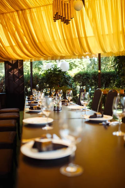 Sparkling glassware stands on long table prepared for wedding dinner.