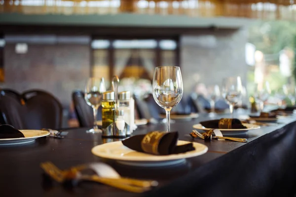 Sparkling glassware stands on long table prepared for wedding dinner.