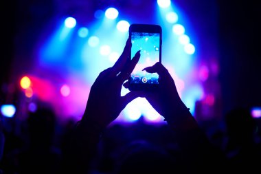 Use advanced mobile recording, fun concerts and beautiful lighting, Candid image of crowd at rock concert, Close up of recording video with smartphone, Enjoy the use of mobile photography clipart