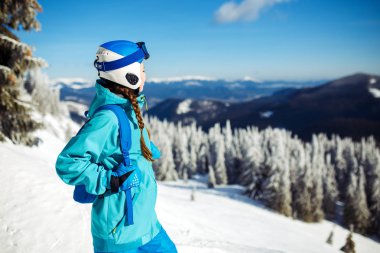 Güzel bir kız kış giysileri, mavi bir kask ve yeşil bir ceket dağlarda harika bir dönemden geçiyor. Seyahat, spor boş zaman, Özgürlük kavramı. Güzel doğa, Yerler, büyük hava durumu. 