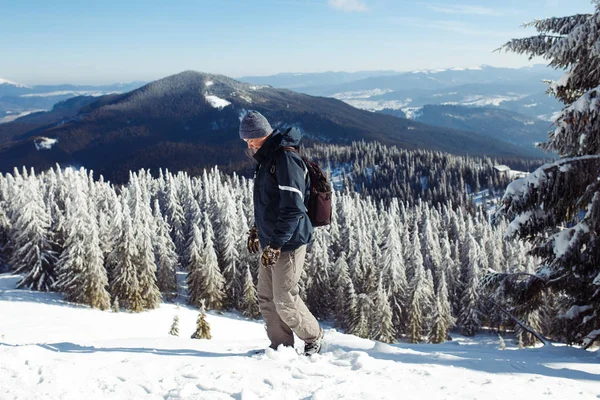 Dağlarda trekking sırt çantası olan adam. Soğuk hava, kar tepelerde. Hiking kış. Kış geliyor, yılın ilk karı yağıyor. seyahat, dinlenme, rahatlama kavramı 