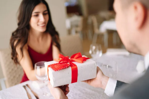 Valentine\'s Day concept. Happy couple in love with. A young loving couple celebrating Valentine\'s Day in the restaurant. Lovers give each other gifts. Romance restaurant for Valentine\'s Day- concept.