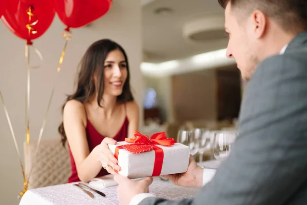 Valentine\'s Day concept. Happy couple in love with. A young loving couple celebrating Valentine\'s Day in the restaurant. Lovers give each other gifts. Romance restaurant for Valentine\'s Day- concept.