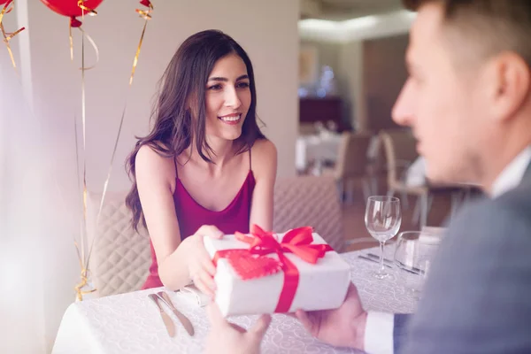 Valentine\'s Day concept. Happy couple in love with. A young loving couple celebrating Valentine\'s Day in the restaurant. Lovers give each other gifts. Romance restaurant for Valentine\'s Day- concept.