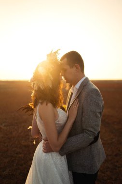 genç ve güzel gelin ve damat hoşlanıyoruz. Düğün günü boho tarzı. Mutlu gelin ve damat açık doğa gün batımında güneş portresi. Sıcak yaz.