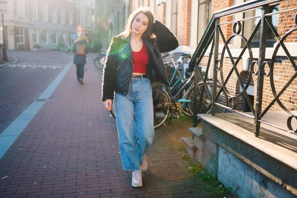 晴れた日に美しい女の子の肖像画 アムステルダムの街 素晴らしい気分 少女は 彼女のライフ スタイルを楽しんでいます 彼女は赤の シャツ ジーンズ 革のジャケットを着ています — ストック写真