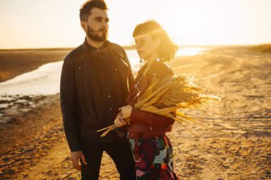 Birlikte eğleniyoruz. Tarz sahibi ve sevgi dolu bir çift deniz kenarında eğleniyor. Çift genç ve aşıklar. Gençlik, aşk ve yaşam tarzı kavramı. Güzel bir yaz gününde gün batımı.