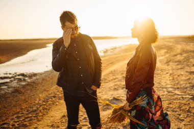 Birlikte eğleniyoruz. Tarz sahibi ve sevgi dolu bir çift deniz kenarında eğleniyor. Çift genç ve aşıklar. Gençlik, aşk ve yaşam tarzı kavramı. Güzel bir yaz gününde gün batımı.