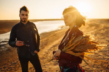 Birlikte eğleniyoruz. Tarz sahibi ve sevgi dolu bir çift deniz kenarında eğleniyor. Çift genç ve aşıklar. Gençlik, aşk ve yaşam tarzı kavramı. Güzel bir yaz gününde gün batımı.