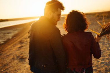 Birlikte eğleniyoruz. Tarz sahibi ve sevgi dolu bir çift deniz kenarında eğleniyor. Çift genç ve aşıklar. Gençlik, aşk ve yaşam tarzı kavramı. Güzel bir yaz gününde gün batımı.