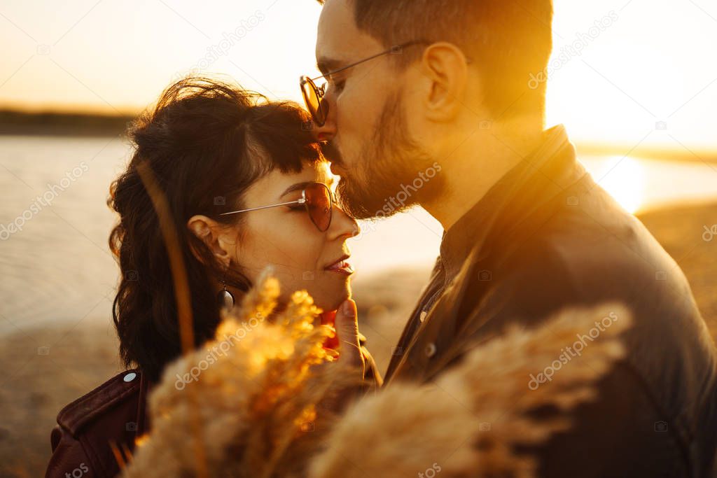 Enjoying time together.  Stylish and loving couple enjoying each other by the sea. The couple is young and in love. The concept of youth, love and lifestyle. Beautiful sunset on a summer day.