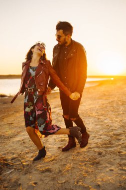 Birlikte eğleniyoruz. Tarz sahibi ve sevgi dolu bir çift deniz kenarında eğleniyor. Çift genç ve aşıklar. Gençlik, aşk ve yaşam tarzı kavramı. Güzel bir yaz gününde gün batımı.