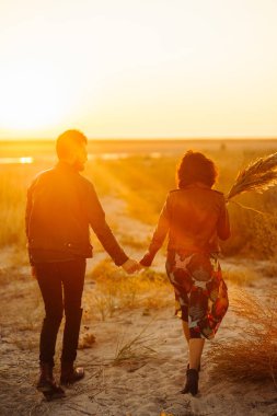 Birlikte eğleniyoruz. Tarz sahibi ve sevgi dolu bir çift deniz kenarında eğleniyor. Çift genç ve aşıklar. Gençlik, aşk ve yaşam tarzı kavramı. Güzel bir yaz gününde gün batımı.