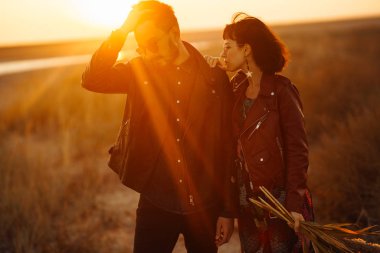 Birlikte eğleniyoruz. Tarz sahibi ve sevgi dolu bir çift deniz kenarında eğleniyor. Çift genç ve aşıklar. Gençlik, aşk ve yaşam tarzı kavramı. Güzel bir yaz gününde gün batımı.