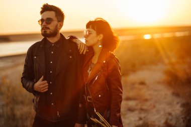 Birlikte eğleniyoruz. Tarz sahibi ve sevgi dolu bir çift deniz kenarında eğleniyor. Çift genç ve aşıklar. Gençlik, aşk ve yaşam tarzı kavramı. Güzel bir yaz gününde gün batımı.