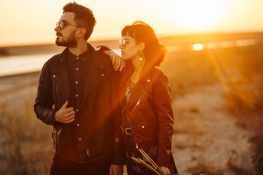 Birlikte eğleniyoruz. Tarz sahibi ve sevgi dolu bir çift deniz kenarında eğleniyor. Çift genç ve aşıklar. Gençlik, aşk ve yaşam tarzı kavramı. Güzel bir yaz gününde gün batımı.