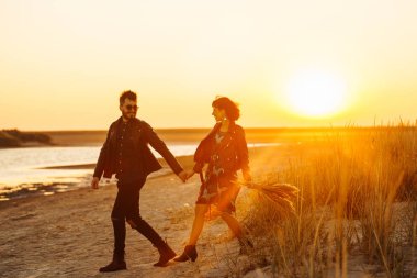 Birlikte eğleniyoruz. Tarz sahibi ve sevgi dolu bir çift deniz kenarında eğleniyor. Çift genç ve aşıklar. Gençlik, aşk ve yaşam tarzı kavramı. Güzel bir yaz gününde gün batımı.