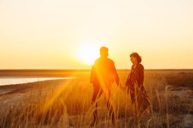Birlikte eğleniyoruz. Tarz sahibi ve sevgi dolu bir çift deniz kenarında eğleniyor. Çift genç ve aşıklar. Gençlik, aşk ve yaşam tarzı kavramı. Güzel bir yaz gününde gün batımı.