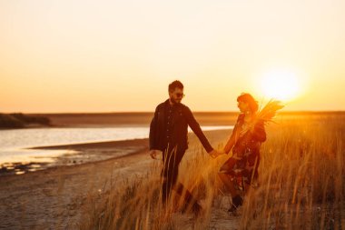Birlikte eğleniyoruz. Tarz sahibi ve sevgi dolu bir çift deniz kenarında eğleniyor. Çift genç ve aşıklar. Gençlik, aşk ve yaşam tarzı kavramı. Güzel bir yaz gününde gün batımı.