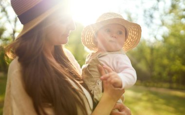 Mutlu şık ve sevgi dolu aile. Anne bebeği ile oynuyor açık. güzel bebek gülümsüyor ve hoşlanır. Annemin gün konsepti. Güzel aile yaz günü dışarıda geçiriyor.