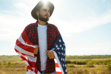 4 Temmuz. 4 Temmuz. Ulusal bayrağı olan Amerikalı. Amerikan bayrağı. Bağımsızlık günü. Vatanseverlik tatili. Adam şapka, sırt çantası, gömlek ve kot giyiyor. Güzel günbatımı ışık. 