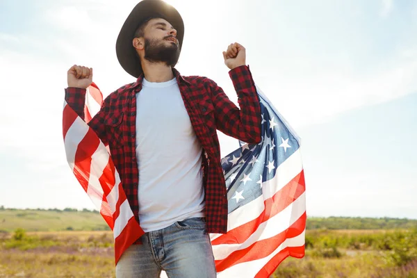 4 Temmuz. 4 Temmuz. Ulusal bayrağı olan Amerikalı. Amerikan bayrağı. Bağımsızlık günü. Vatanseverlik tatili. Adam şapka, sırt çantası, gömlek ve kot giyiyor. Güzel günbatımı ışık. 