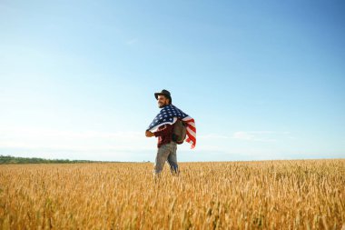 4 Temmuz. 4 Temmuz. Ulusal bayrağı olan Amerikalı. Amerikan bayrağı. Bağımsızlık günü. Vatanseverlik tatili. Adam şapka, sırt çantası, gömlek ve kot giyiyor. Güzel günbatımı ışık. 