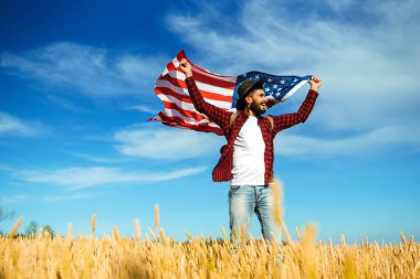4 Temmuz. 4 Temmuz. Ulusal bayrağı olan Amerikalı. Amerikan bayrağı. Bağımsızlık günü. Vatanseverlik tatili. Adam şapka, sırt çantası, gömlek ve kot giyiyor. Güzel günbatımı ışık. 
