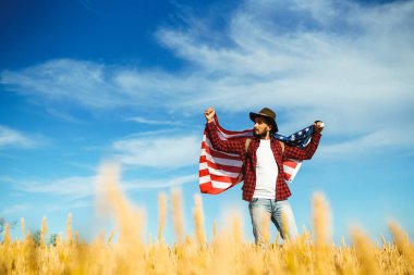 4 Temmuz. 4 Temmuz. Ulusal bayrağı olan Amerikalı. Amerikan bayrağı. Bağımsızlık günü. Vatanseverlik tatili. Adam şapka, sırt çantası, gömlek ve kot giyiyor. Güzel günbatımı ışık. 