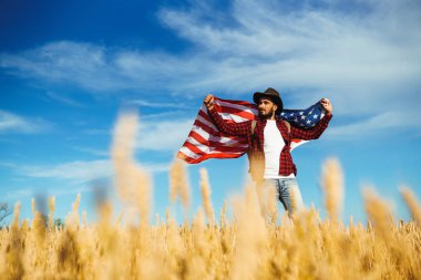 4 Temmuz. 4 Temmuz. Ulusal bayrağı olan Amerikalı. Amerikan bayrağı. Bağımsızlık günü. Vatanseverlik tatili. Adam şapka, sırt çantası, gömlek ve kot giyiyor. Güzel günbatımı ışık. 