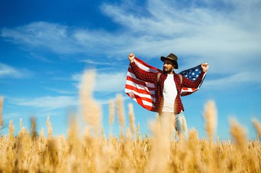 4 Temmuz. 4 Temmuz. Ulusal bayrağı olan Amerikalı. Amerikan bayrağı. Bağımsızlık günü. Vatanseverlik tatili. Adam şapka, sırt çantası, gömlek ve kot giyiyor. Güzel günbatımı ışık. 