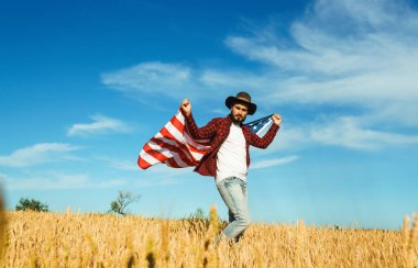 4 Temmuz. 4 Temmuz. Ulusal bayrağı olan Amerikalı. Amerikan bayrağı. Bağımsızlık günü. Vatanseverlik tatili. Adam şapka, sırt çantası, gömlek ve kot giyiyor. Güzel günbatımı ışık. 