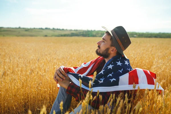 4 Temmuz. 4 Temmuz. Ulusal bayrağı olan Amerikalı. Amerikan bayrağı. Bağımsızlık günü. Vatanseverlik tatili. Adam şapka, sırt çantası, gömlek ve kot giyiyor. Güzel günbatımı ışık. 