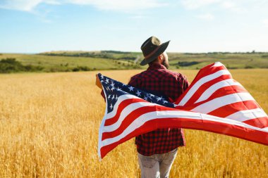 4 Temmuz. 4 Temmuz. Ulusal bayrağı olan Amerikalı. Amerikan bayrağı. Bağımsızlık günü. Vatanseverlik tatili. Adam şapka, sırt çantası, gömlek ve kot giyiyor. Güzel günbatımı ışık. 