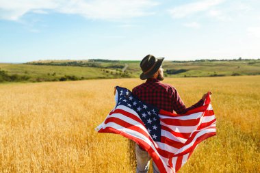 4 Temmuz. 4 Temmuz. Ulusal bayrağı olan Amerikalı. Amerikan bayrağı. Bağımsızlık günü. Vatanseverlik tatili. Adam şapka, sırt çantası, gömlek ve kot giyiyor. Güzel günbatımı ışık. 