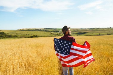 4 Temmuz. 4 Temmuz. Ulusal bayrağı olan Amerikalı. Amerikan bayrağı. Bağımsızlık günü. Vatanseverlik tatili. Adam şapka, sırt çantası, gömlek ve kot giyiyor. Güzel günbatımı ışık. 