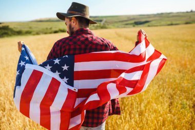 4 Temmuz. 4 Temmuz. Ulusal bayrağı olan Amerikalı. Amerikan bayrağı. Bağımsızlık günü. Vatanseverlik tatili. Adam şapka, sırt çantası, gömlek ve kot giyiyor. Güzel günbatımı ışık. 