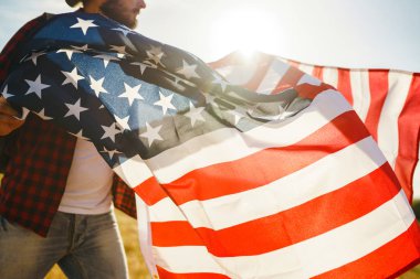 4 Temmuz. 4 Temmuz. Ulusal bayrağı olan Amerikalı. Amerikan bayrağı. Bağımsızlık günü. Vatanseverlik tatili. Adam şapka, sırt çantası, gömlek ve kot giyiyor. Güzel günbatımı ışık. 