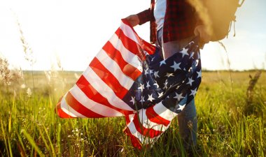 4 Temmuz. 4 Temmuz. Ulusal bayrağı olan Amerikalı. Amerikan bayrağı. Bağımsızlık günü. Vatanseverlik tatili. Adam şapka, sırt çantası, gömlek ve kot giyiyor. Güzel günbatımı ışık. 
