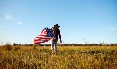 4 Temmuz. 4 Temmuz. Ulusal bayrağı olan Amerikalı. Amerikan bayrağı. Bağımsızlık günü. Vatanseverlik tatili. Adam şapka, sırt çantası, gömlek ve kot giyiyor. Güzel günbatımı ışık. 