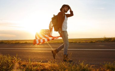 4 Temmuz. 4 Temmuz. Ulusal bayrağı olan Amerikalı. Amerikan bayrağı. Bağımsızlık günü. Vatanseverlik tatili. Adam şapka, sırt çantası, gömlek ve kot giyiyor. Güzel günbatımı ışık. 