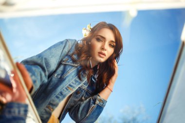 Güzel bir gelinin portresi. Düğün konsepti. Şık bir düğün. Harika gün batımı ışığı. Mavi kot ceket giyiyor, elbise. Bahar çiçekli bahçe..