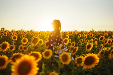 Ayçiçeği tarlasında Amerikan bayrağı olan güzel bir kız. 4 Temmuz. 4 Temmuz. Özgürlük. Gün batımı ışığı Kız gülümsüyor. Güzel gün batımı. Bağımsızlık Günü. Vatansever tatil. 