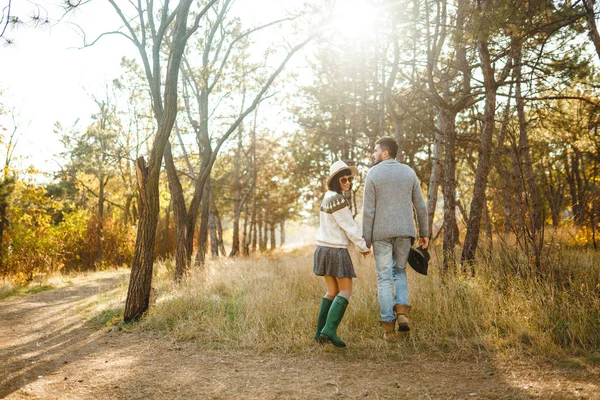 Lovely hipster couple looking at each other. Couple wearing beautiful hats and sweaters. Lifestyle, happy couple of two play on a sunny day in the park. The concept of youth, love and lifestyle. Sunset in autumn