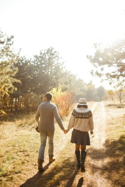 Güzel hipster çift birbirlerine bakıyor. Güzel şapkalar ve kazaklar giyen bir çift. Yaşam tarzı, parkta güneşli bir günde iki oyun mutlu çift. Gençlik, sevgi ve yaşam tarzı kavramı. Sonbaharda gün batımı 
