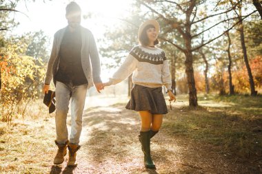 Güzel hipster çift birbirlerine bakıyor. Güzel şapkalar ve kazaklar giyen bir çift. Yaşam tarzı, parkta güneşli bir günde iki oyun mutlu çift. Gençlik, sevgi ve yaşam tarzı kavramı. Sonbaharda gün batımı 