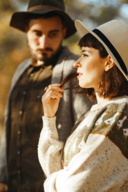 Güzel hipster çift birbirlerine bakıyor. Güzel şapkalar ve kazaklar giyen bir çift. Yaşam tarzı, parkta güneşli bir günde iki oyun mutlu çift. Gençlik, sevgi ve yaşam tarzı kavramı. Sonbaharda gün batımı 