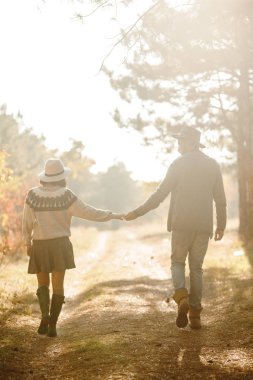 Güzel hipster çift birbirlerine bakıyor. Güzel şapkalar ve kazaklar giyen bir çift. Yaşam tarzı, parkta güneşli bir günde iki oyun mutlu çift. Gençlik, sevgi ve yaşam tarzı kavramı. Sonbaharda gün batımı 