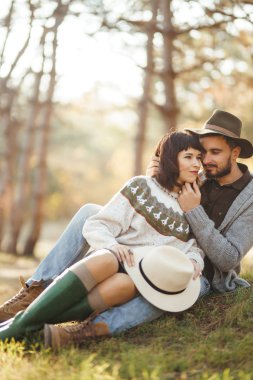 Güzel hipster çift birbirlerine bakıyor. Güzel şapkalar ve kazaklar giyen bir çift. Yaşam tarzı, parkta güneşli bir günde iki oyun mutlu çift. Gençlik, sevgi ve yaşam tarzı kavramı. Sonbaharda gün batımı 